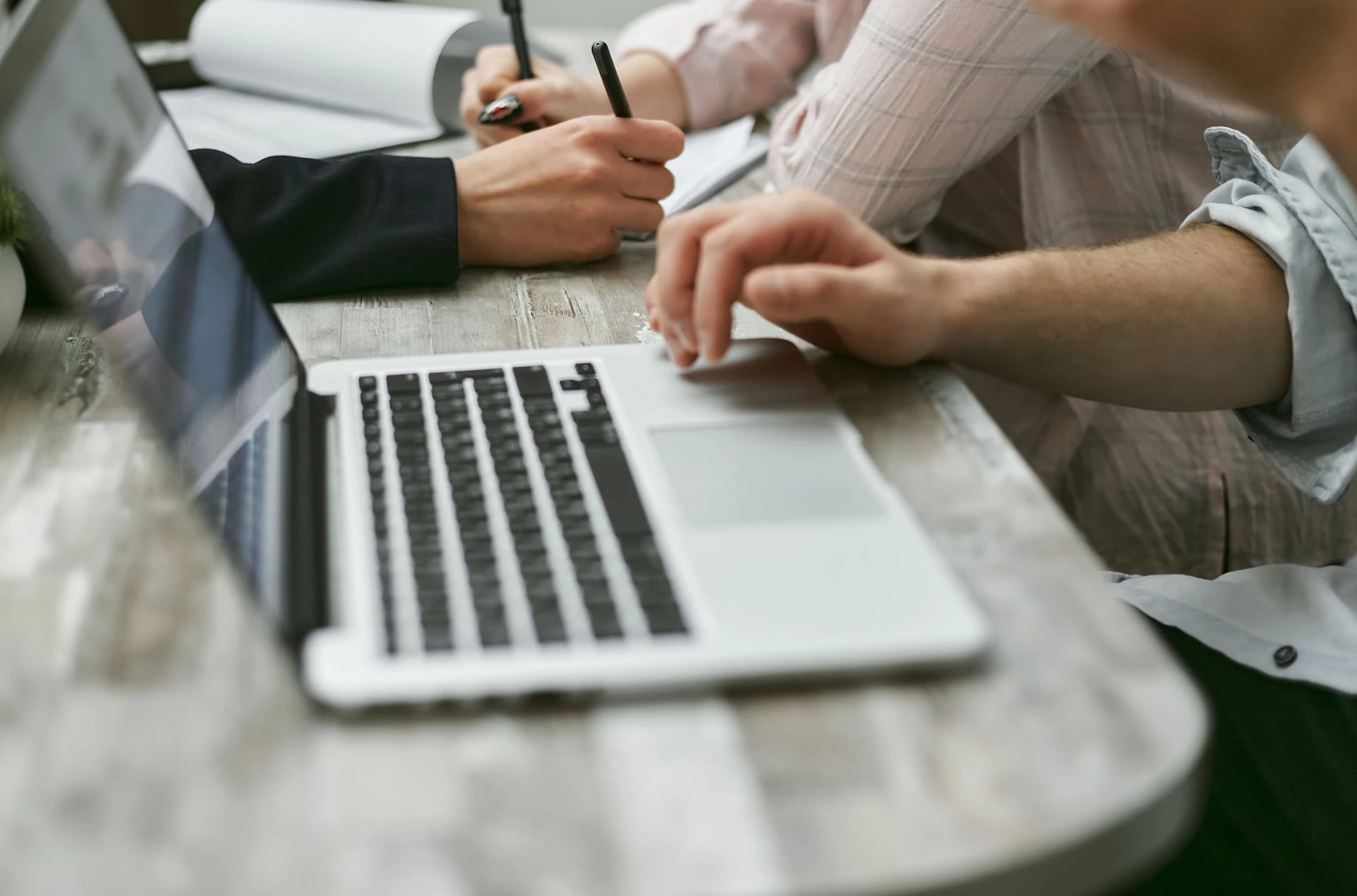 Colleagues taking notes beside a laptop